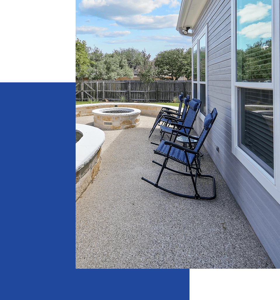 A patio with chairs and fire pit in the background.