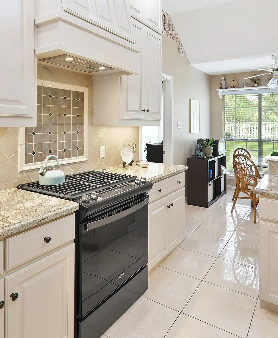 A kitchen with white cabinets and black appliances.