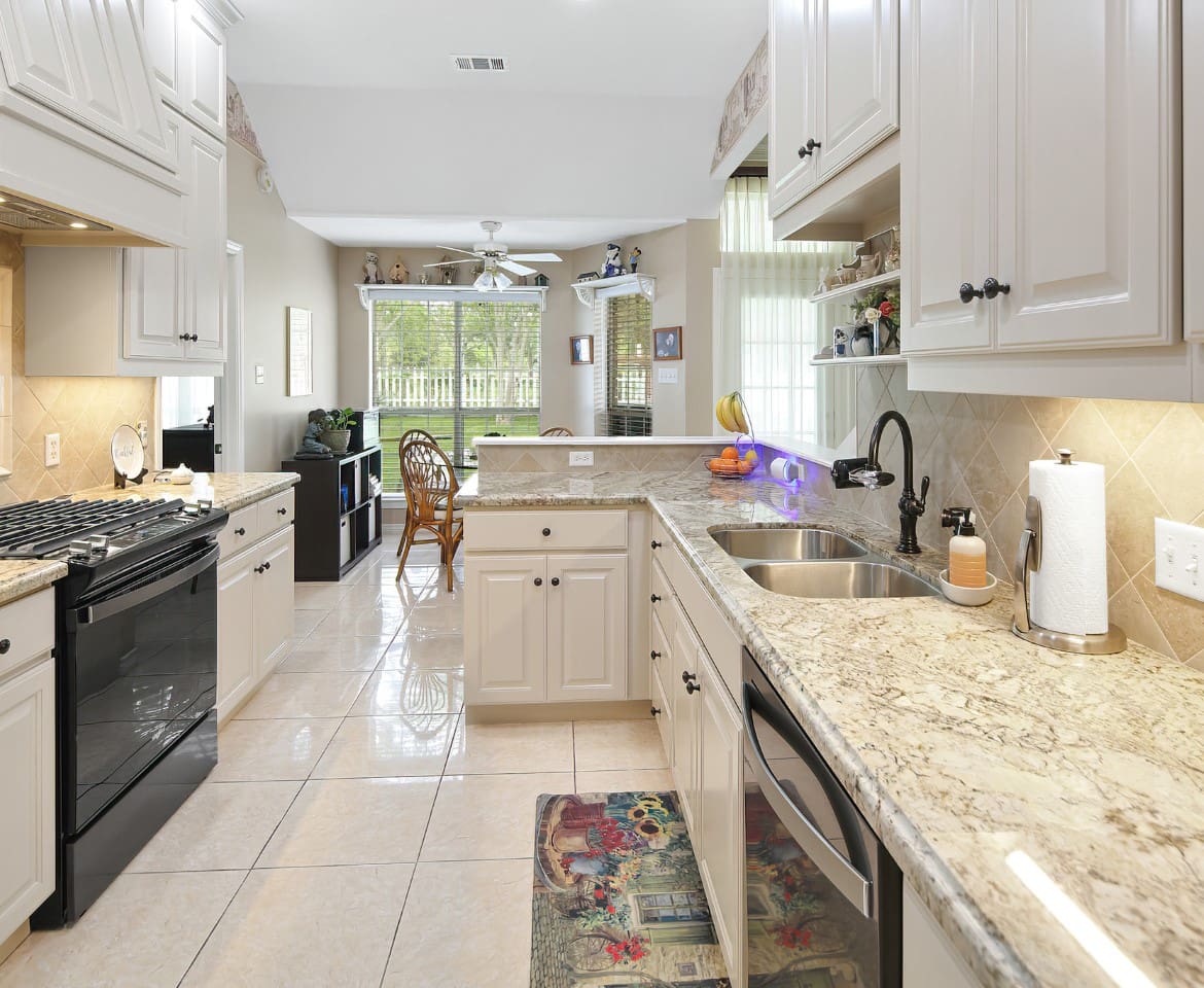 A kitchen with white cabinets and black appliances.