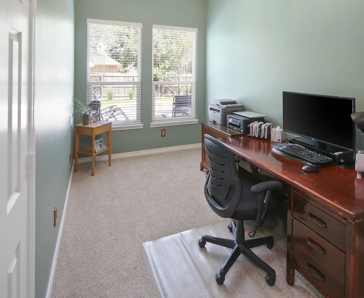 A desk with a computer and chair in the corner of a room.