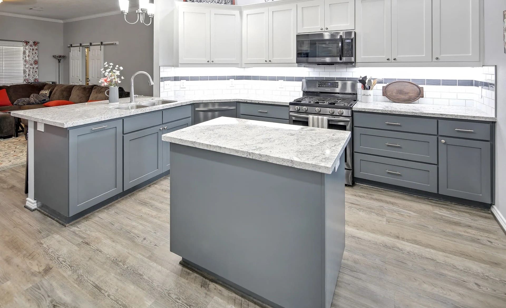 A kitchen with white cabinets and grey island.