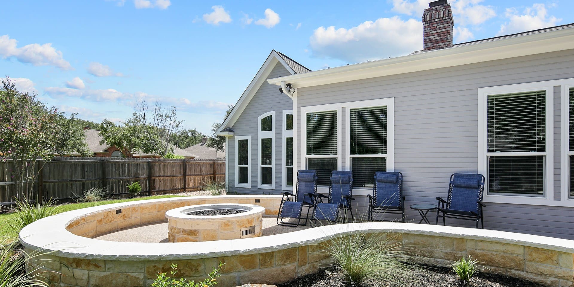 A backyard with a fire pit and chairs.