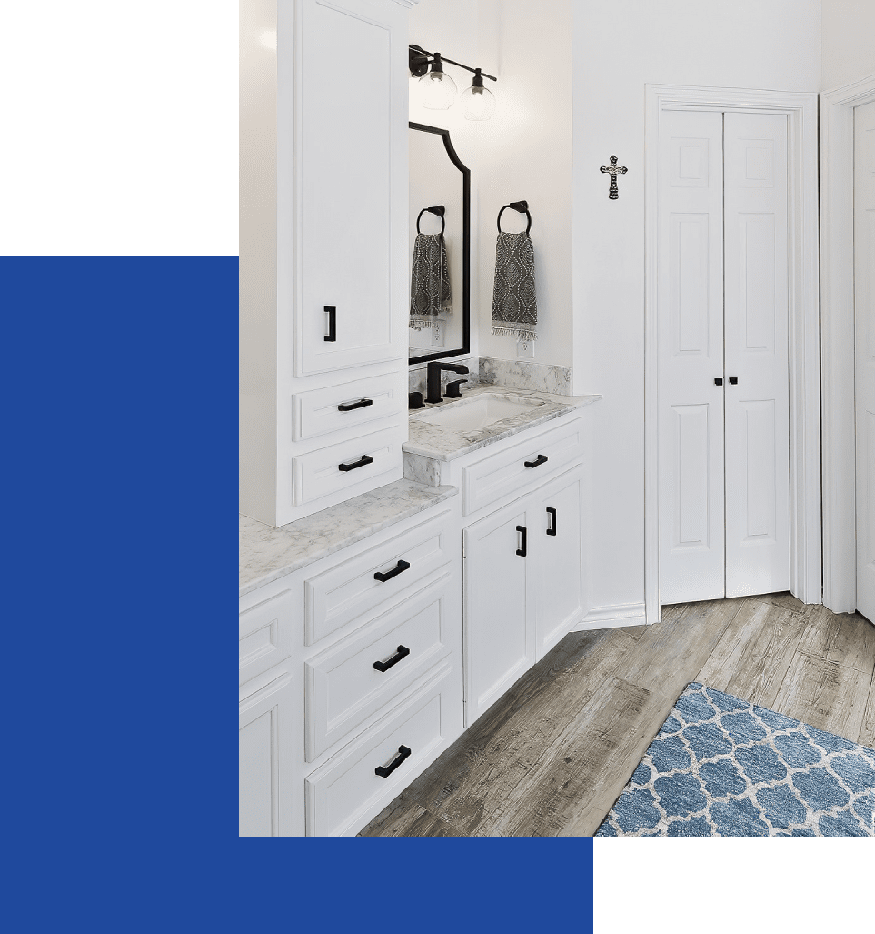 A bathroom with white cabinets and blue rug.