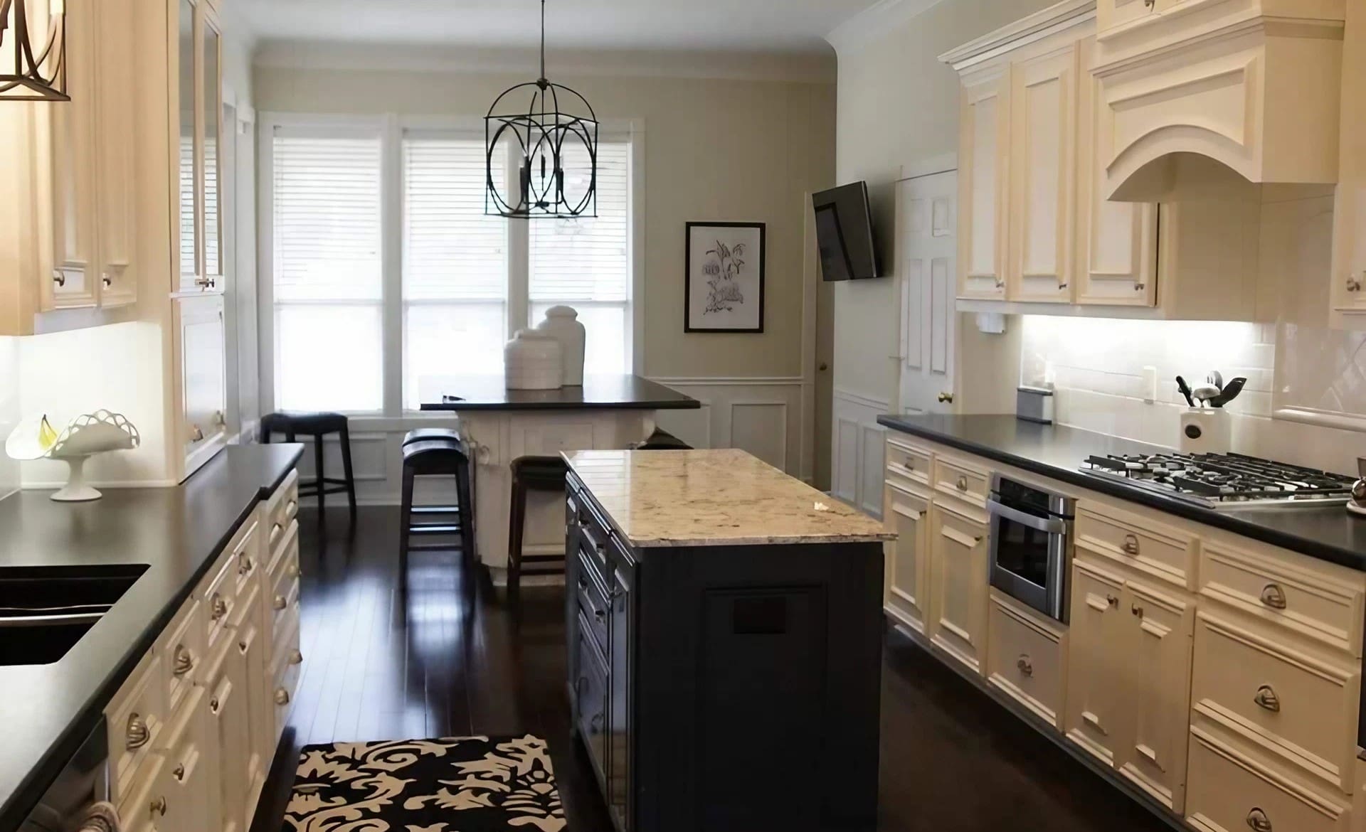 A kitchen with white cabinets and black island.